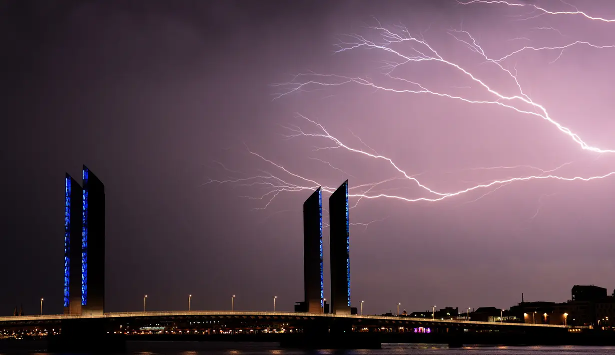 Kilatan petir yang terlihat diatas jembatan Bordeaux, Prancis (18/7). Kilatan ini hiasi langit Prancis saat terjadi badai petir. (AFP Photo/Nicolas Tucat)