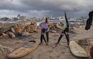 Warga Palestina, Khalil Abu Jayyab (kanan) dan Tahseen Abu Assi melakukan pemanasan sebelum berselancar di pantai Kota Gaza, Minggu, 28 Desember 2025. Pasca diberlakukannya gencatan senjata fase pertama yang didukung oleh Amerika Serikat mulai berlaku pada 10 Oktober 2025, warga Palestina mulai kembali ke Kota Gaza. (AP Photo/Jehad Alshrafi)