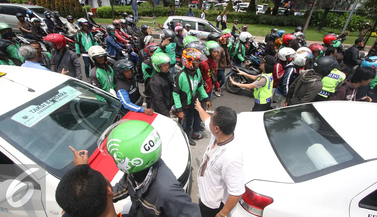 Petugas menenangkan pengadara Go-Jek yang terlibat kericuhan di Jakarta, Selasa (22/3). Ratusan Go-Jek mendatangi para sopir taksi karena tersebar isu pemukulan terhadap beberapa pengendara Go-Jek oleh sopir taksi.  (Liputan6.com/Immanuel Antonius)