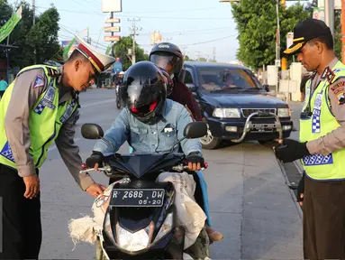Petugas Kepolisian memberhentikan pengendara motor di Simpang Maya, Tegal, Jawa Tengah Minggu (10/7). Pemberhentian dilakukan untuk mengecek barang bawaan agar tidak membahayakan pengendara lain. (Liputan6.com/Herman Zakharia)