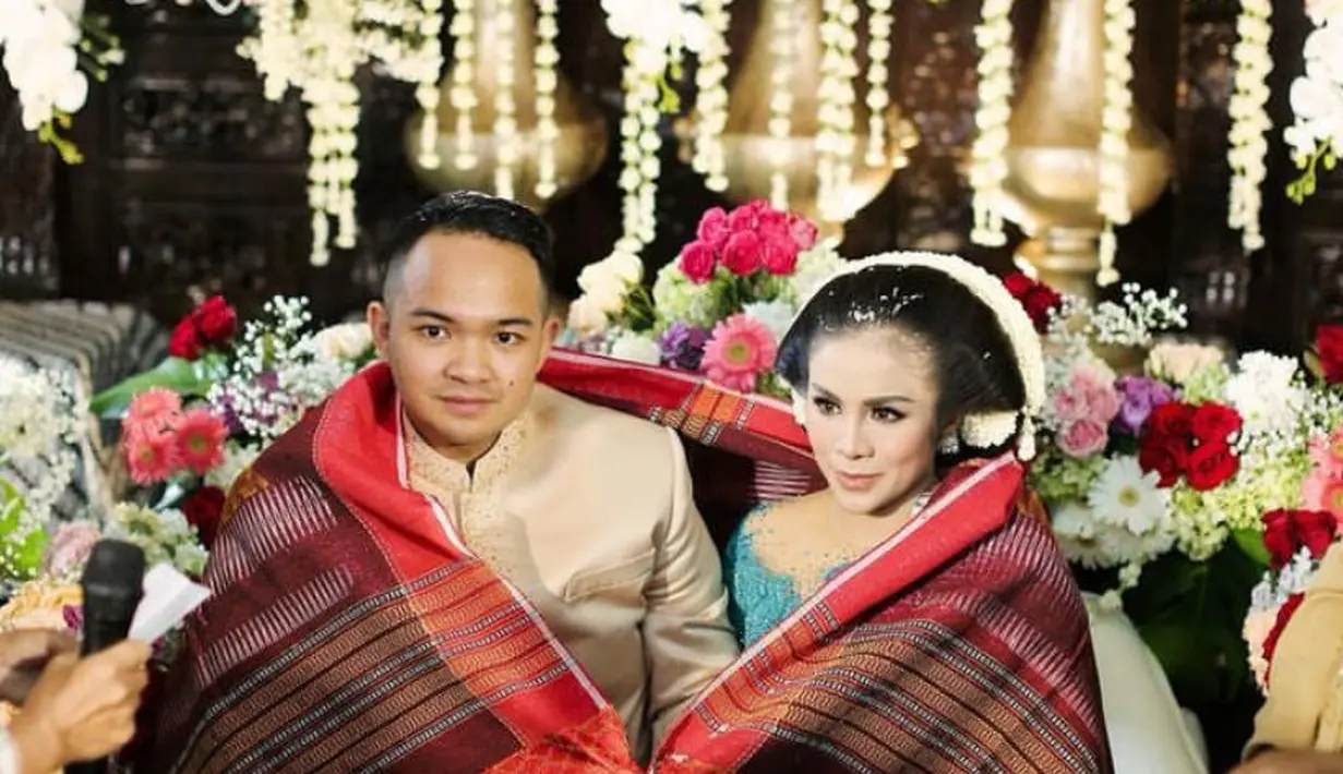 7 bulanan momo cukup unik, ia menggabungkan adat Batak dan Jawa. Momo tampil dengan kebaya biru dan sang suami mengenakan beskap. Keduanya dililitkan kain ulos merah. [@therealmomogeisha]