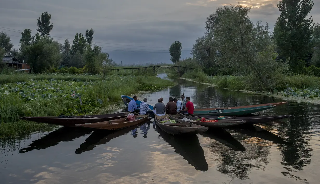 Laki-laki Kashmir mengobrol saat beristirahat sambil menjual produk mereka di pasar sayur terapung di Danau Dal, Srinagar, Kashmir, India, Sabtu (7/8/2021). Pedagang menghabiskan waktu bertahun-tahun untuk memelihara Danau Dal dari rumput liar. (AP Photo/Dar Yasin)