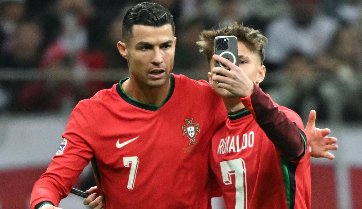 Seorang penyusup lapangan melakukan swafoto dengan pemain Portugal, Cristiano Ronaldo (kiri) saat laga lanjutan EUFA Nations League Polandia di National Stadium, Warsawa, Polandia, Minggu (13/10/2024) WIB. (AFP/Sergei Gapon)