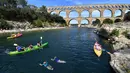 Wisatawan bermain kayak di dekat Pont du Gard atau Jembatan Gard di Vers-Pont-du-Gard, Prancis, Rabu (21/8/2019). Pont du Gard merupakan jembatan saluran air dari batu yang terdiri dari tiga tingkatan. (Pascal GUYOT/AFP)