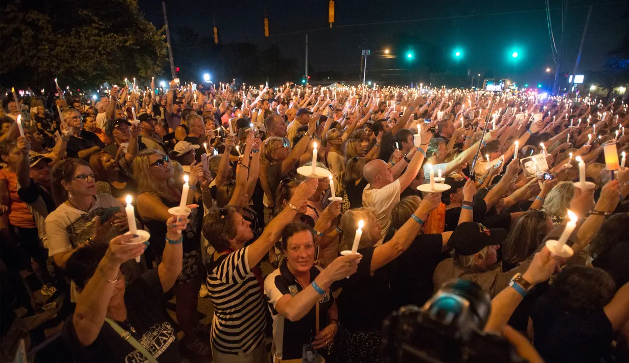 Para penggemar menyalakan lilin dalam peringatan 40 tahun kematian Elvis Presley di depan bekas rumahnya di Graceland, Memphis, Tennessee, Selasa (15/8). Elvis Presley meninggal pada 16 Agustus 1977 silam karena serangan jantung. (AP Photo/Brandon Dill)