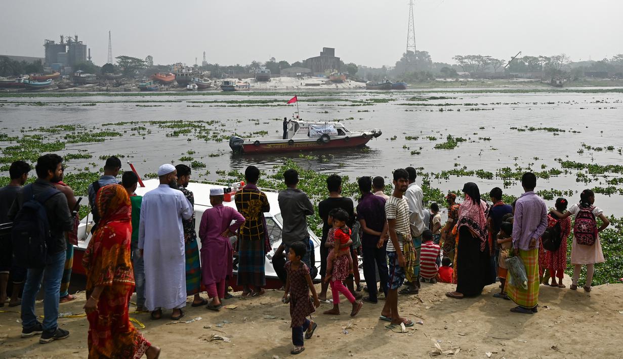 Orang-orang menyaksikan petugas pemadam kebakaran mencari korban kecelakaan feri di Sungai Shitalakshya di Narayanganj, Bangladesh (21/3/2022). Feri ML Afsar Uddin tenggelam di sungai setelah ditabrak kapal kargo. (AFP/Munir uz Zaman)