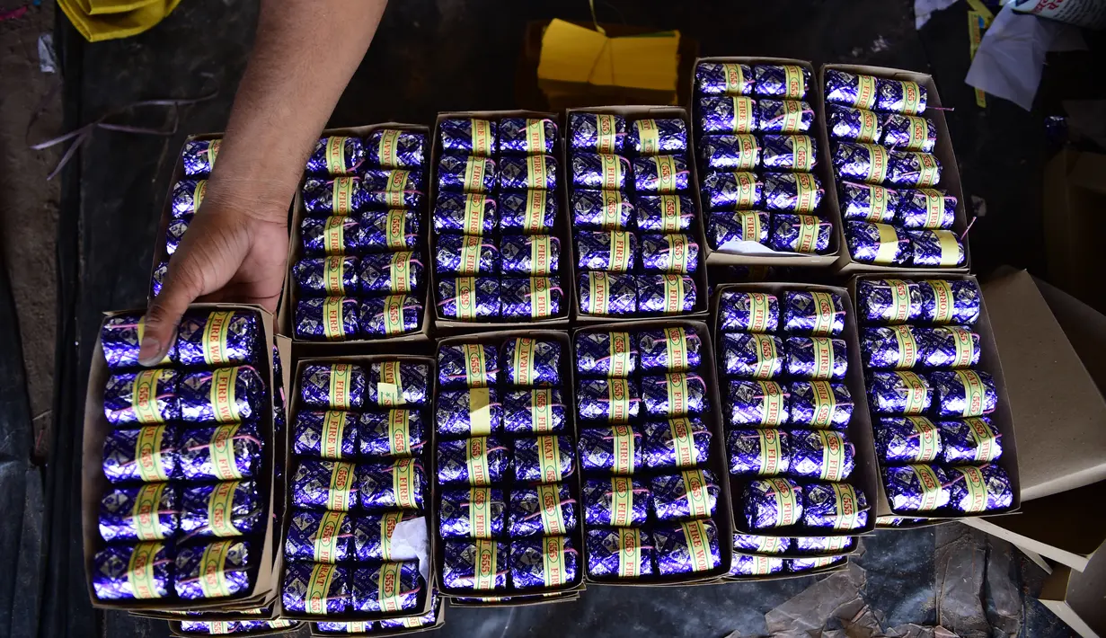 Seorang pekerja menumpuk petasan yang sudah jadi di sebuah bengkel menjelang festival Diwali di pinggiran Ahmedabad, India (21/9/2022). Perayaan ini terfokus pada lampu dan cahaya, terutama pada lampu "diya" tradisional. (AFP/Sam Panthaky)
