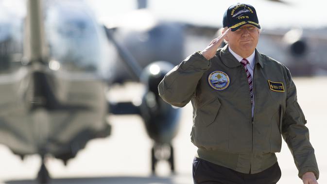 Presiden AS, Donald Trump memberi hormat saat berjalan menuju pesawat Air Force One sebelum berangkat dari Pangkalan Udara Langley di Virginia, (2/3). Trump tampak gagah mengenakan jaket panglima tertinggi Navy Seal. (AFP Photo / Saul Loeb)
