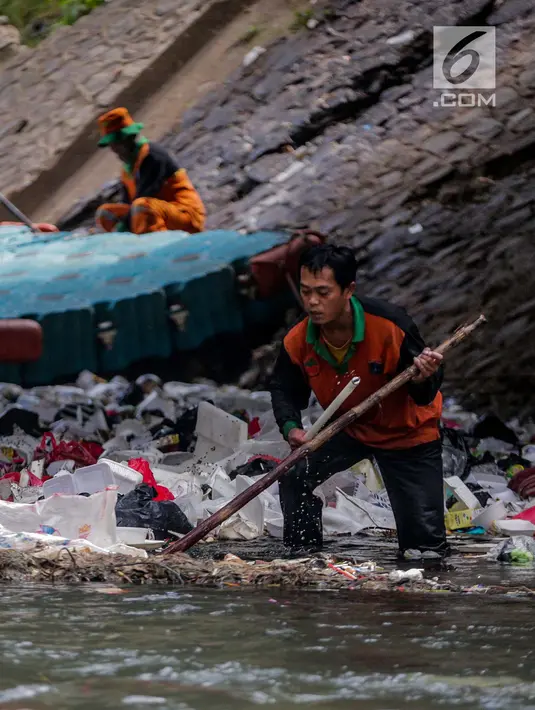 Aksi petugas PPSU bersihkan sampah yang tersangkut ditengah deras arus aliran anak kali Ciliwung, Jakarta, Senin (22/7/2019). Pembersihan sungai dari berbagai sampah tersebut dimaksudkan agar tidak ada penumpukan sampah dan sedimentasi saluran di sepanjang sungai. (Liputan6.com/Faizal Fanani)
