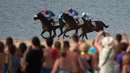  Para joki memacu kudanya dalam pacuan kuda pantai di Sanlucar de Barrameda, Spanyol, (27/8/2016). (AFP/Jorge Guerrero)