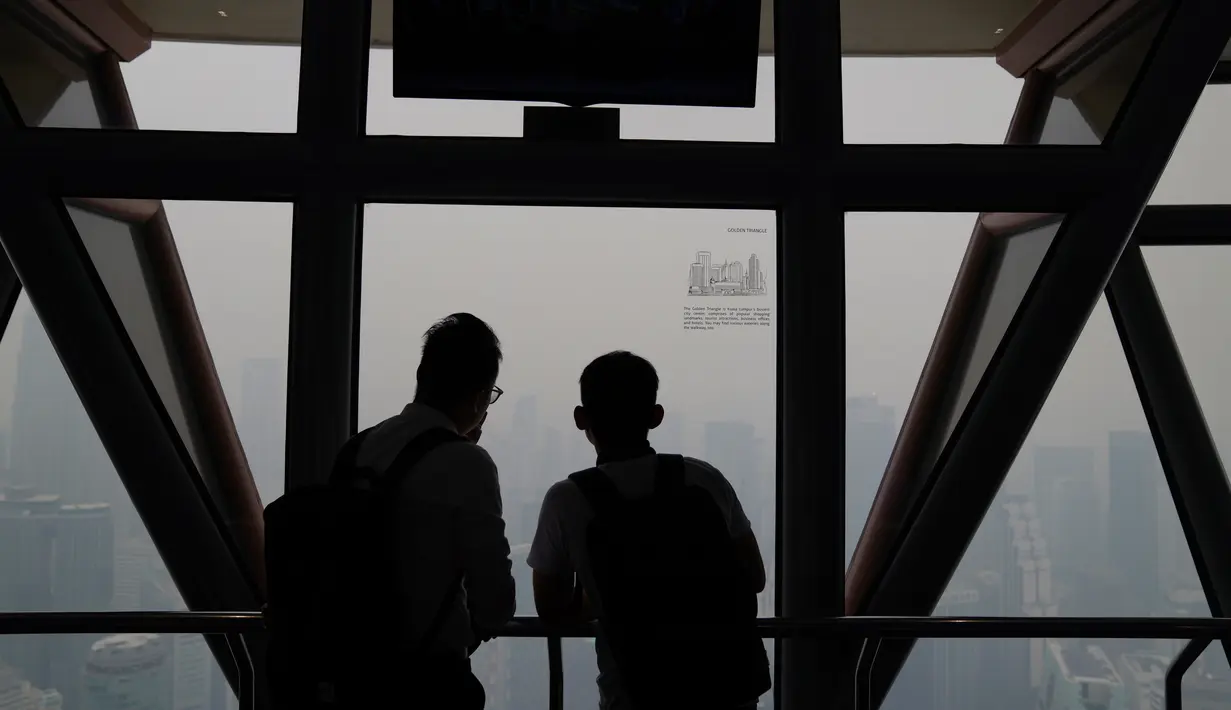 Wisatawan melihat pemandangan kota yang diselimuti kabut asap pekat dari Kuala Lumpur Tower, Kuala Lumpur, Malaysia, Jumat (13/9/2019).  Pemerintah Malaysia berencana membuat hujan buatan untuk mengurangi kabut asap. (AP Photo/Vincent Thian)