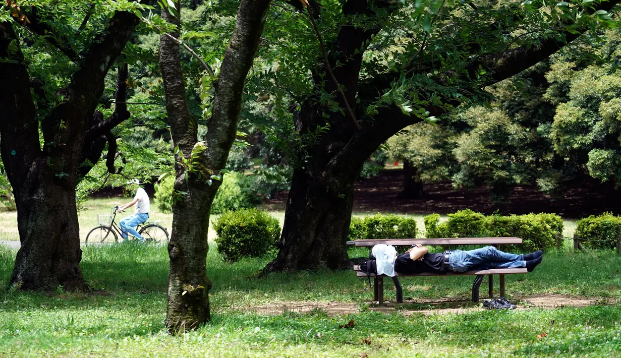 Seorang pria berbaring di bangku di sebuah taman di Tokyo (11/6/2020). Cuaca panas terus berlanjut di wilayah metropolitan karena suhunya diperkirakan akan naik menjadi 31 derajat Celsius (87,8 derajat Fahrenheit), menurut biro meteorologi Jepang. (AP Photo/Eugene Hoshiko)
