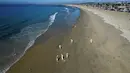 Pekerja membersihkan minyak dari pasir di Pantai Newport, California, Amerika Serikat, Selasa (5/10/2021). Kebocoran pipa menyebabkan tumpahan minyak di lepas pantai California. (Jeff Gritchen/The Orange County Register via AP)