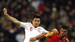 Bek Inggris, Harry Maguire (kiri) berebut bola dengan penyerang Montenegro, Fatos selama pertandingan Grup A Kualifikasi Piala Eropa 2020 di Stadion Wembley di London (14/11/2019). Inggris menang telak 7-0 atas Montenegro. (AFP/Adrian Dennis)