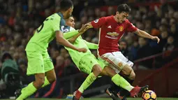 Bek Manchester United, Matteo Dramian, berusaha lepas dari hadangan gelandang Liverpool, Roberto Firmino. Perbandingan penguasaan bola kedua tim relatif berjalan seimbang, keduanya saling bertukar serangan. (AFP/Oli Scarff)
