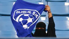 Seorang wanita mengibarkan bendera saat mendukung tim Al-Hilal dari Saudi melawan Al-Ittihad dalam pertandingan Liga Saudi Pro di King Fahd International Stadium di Riyadh (13/1). (AFP Photo/Ali Al-Arifi)