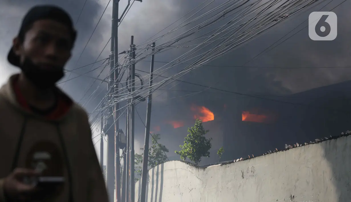 Asap hitam membumbung dari atas Gudang JNE Express yang terbakar di Jalan Pekapuran Raya, Depok, pada Senin (12/9/2022). JNE menjamin barang milik konsumen yang rusak  dalam peristiwa kebakaran gudang di Depok akan diganti. (Liputan6.com/Herman Zakharia)