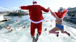 Sejumlah peserta mengenakan kostum Sinterklas dalam perlombaan renang bertajuk Copa Nadal (Piala Natal) edisi ke-115 yang berlangsung di Port Vell, Barcelona, Spanyol, Rabu (25/12/2024). Ajang tersebut diikuti oleh 450 peserta dengan jarak renang sejauh 200 meter. (AFP/Josep Lago)