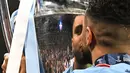 Gelandang Manchester City, Riyad Mahrez mencium trofi Liga Champions dalam perayaan kemenangan atas Inter Milan pada laga Final Liga Champions 2022/2023 di Ataturk Olympic Stadium, Istanbul, (10/6/2023). Gelar ini juga menjadi yang pertama baginya. (AFP/Paul Ellis)