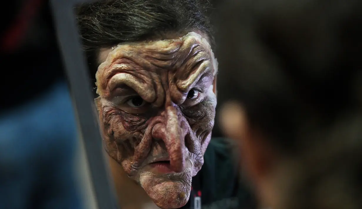 Seorang pria mengenakan topeng berias untuk mengikuti acara ScareLA 'Monsters Come Together' di Los Angeles, California (6/8). Acara ini juga menjadi ajang berkumpulnya bagi para penggemar film horor. (AFP Photo/Mark Ralston)