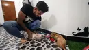 Mahasiswa kedokteran hewan, Ahmad Taher memberi makan kucing yang menginap di hotel khusus kucing di Basra, Irak, 28 Maret 2018. Hotel itu memberikan tempat bernaung yang layak bagi kucing ketika para pemilikinya bepergian jauh. (HAIDAR MOHAMMED ALI/AFP)