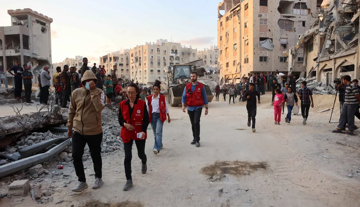 Warga bersama anggota Komite Internasional Palang Merah (ICRC) berkumpul di lokasi di mana orang-orang sedang menggali dengan ekskavator untuk mencari korban serangan Israel di antara reruntuhan bangunan di Khan Yunis, bagian selatan Jalur Gaza, pada 17 Oktober 2025. (Omar AL-QATTAA/AFP)