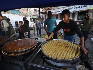 Penjual Palestina menyiapkan manisan di kios mereka di pasar menjelang buka puasa selama bulan suci Ramadhan di kota Rafah, Jalur Gaza selatan, pada 10 April 2022. (SAID KHATIB / AFP)