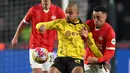 Pemain Borussia Dortmund, Donyell Malen (tengah) berebut bola dengan pemain PSV, Sergino Dest (kanan) pada laga leg pertama 16 besar Liga Champions 2023/2024 di The Philips Stadium, Eindhoven, Belanda, Rabu (21/02/2024) dini hari WIB. (AFP/John Thys)