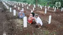 Keluarga berdoa depan pusara makam korban Covid-19 di TPU Srengseng Sawah 2, Jakarta Selatan, Jumat (19/3/2021). Seminggu terakhir intensitas pemakaman korban Covid-19 menurun drastis sebesar rata-rata 20 jenazah/minggu dibandingkan sebelumnya rata-rata 35 jenazah/minggu. (merdeka.com/Arie Basuki)