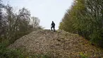 Aktivis lingkungan merekam konten untuk media sosial di tumpukan besar sampah yang dibuang sembarangan, yang ditumpuk di sebuah ladang antara Sungai Cherwell dan Jalan A34 dekat Kidlington, Oxfordshire, di barat London pada 16 November 2025. Gunungan atau tumpukan sampah ilegal berukuran raksasa ditemukan di sebuah ladang di tepi Sungai Cherwell dekat Kidlington, Oxfordshire, Inggris. (Justin TALLIS/AFP)