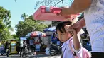 Seorang pria menggunakan tas sekolah untuk melindungi seorang anak dari sengatan matahari saat mereka meninggalkan sekolah di Manila, Filipina pada Senin 3 Maret 2025. (Jam STA ROSA/AFP)