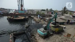 Alat berat mengangkat material endapan lumpur di Kampung Nelayan Cilincing, Jakarta Utara, Kamis (2/9/2021). Pengerukan dilakukan untuk mengurangi pendangkalan di muara teluk Jakarta serta penataan sandaran kapal-kapal tradisional. (merdeka.com/Imam Buhori)