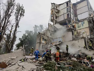 Tim penyelamat membersihkan puing-puing saat bekerja di lokasi bangunan tempat tinggal yang hancur akibat serangan udara Rusia di Kyiv pada 31 Juli 2025. (Tetiana DZHAFAROVA/AFP)
