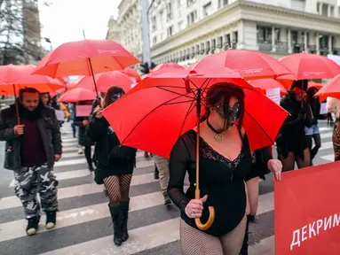 Sejumlah pekerja seks membawa payung merah saat menggelar unjuk rasa di Skopje, Makedonia, Senin (17/12). Mereka menyerukan dihentikannya kekerasan terhadap pekerja seks dan penerapan hukuman bagi pelakunya. (Robert ATANASOVSKI/AFP)