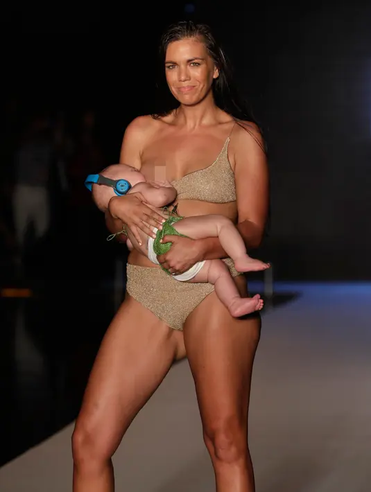 Model Mara Martin berpose di atas runway sambil menyusui bayinya selama Miami Swim Week 2018 di Florida, Minggu (15/8). Mara Martin memamerkan pakaian renangnya saat memberi air susu ibu (ASI) kepada Aria yang berusia lima bulan. (AP/Lynne Sladky)