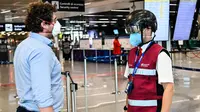 Petugas mengenakan termoscanner portabel "Smart-Helmet" untuk memeriksa suhu penumpang dan sesama staf di terminal keberangkatan bandara Fiumicino Roma, Italia pada 5 Mei 2020. Hal ini dilakukan guna menyaring orang yang memiliki gejala infeksi virus corona. (ANDREAS SOLARO/AFP)