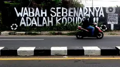 Pengendara melintas di depan mural yang berisi kritikan di Jalan Raya Bogor, Depok, Jawa Barat, Minggu (19/9/2021). Kritik terhadap pemerintah lewat coretan dinding atau mural sempat menjadi polemik karena dihapus. (Liputan6.com/Helmi Fithriansyah)
