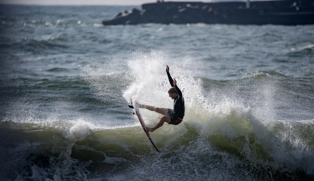 Atlet selancar asal Amerika Serikat, John John Florence berusaha menembus ombak dalam sesi bebas selama Olimpiade Tokyo 2020 di Pantai Tsurigasaki, Chiba, Senin (26/7/2021). (Foto: AFP/Olivier Morin)