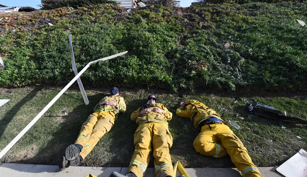 Petugas pemadam kebakaran berbaring di atas tanah setelah kelelahan mengatasi kebakaran yang disebut Lilac Fire di Bonsall, California, Jumat (8/12). Negara bagian tesebut memberlakukan keadaan darurat yang dipicu oleh kebakaran hutan. (Robyn Beck/AFP)