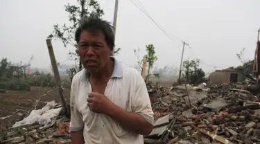 Seorang pria berdiri di depan puing bangunan rumahnya akibat tornado menyapu wilayah Yancheng, Provinsi Jiangsu, Tiongkok, Kamis (23/6). Cuaca ekstrim termasuk hujan es, hujan lebat, dan angin puting beliung itu menewaskan sedikitnya 51 orang. (STR/AFP)