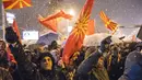 Pengunjuk rasa mengibarkan bendera Macedonia saat menggelar protes di depan gedung Parlemen, Skopje, Selasa (27/2). Di tengah hujan salju, mereka turun ke jalan memprotes wacana pengubahan nama negara mereka. (Robert ATANASOVSKI/AFP)
