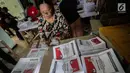 Seorang ibu menyelesaikan pelipatan surat suara Pemilihan Umum 2019 di gudang logistik KPU Jakarta Pusat, Selasa (19/2). Tugas pertama para pekerja ialah menyortir surat suara antara surat suara yang cacat dan yang tidak cacat (Liputan6.com/Faizal Fanani)