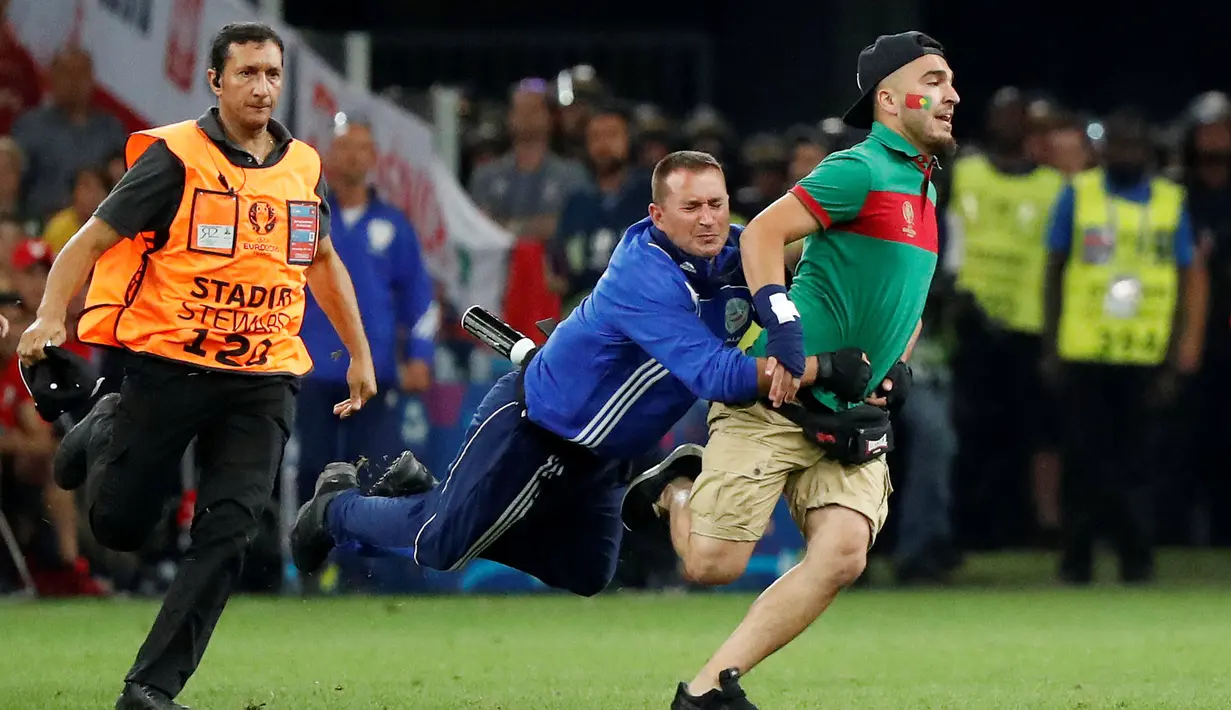Petugas keamanan menangkap suporter yang masuk ke lapangan saat Portugal bersua Polandia pada perempat final Piala Eropa 2016 di Stade VÈlodrome, Marseille, Pranci, (30/6/2016) dini hari WIB. (REUTERS/Kai Pfaffenbach)
