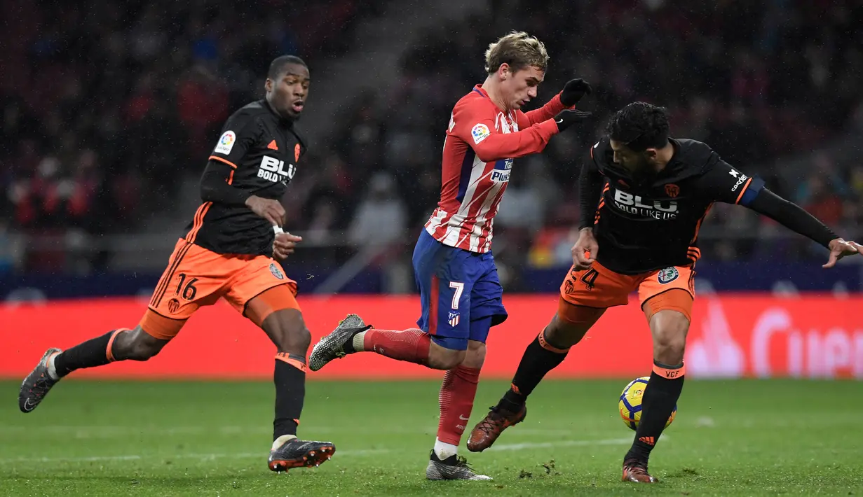 Pemain depan asal Atletico Madrid Antoine Griezmann berusaha melewati dua pemain Valencia saat pertandingan Liga Spanyol di stadion Wanda Metropolitano, Madrid (4/2). Atletico Madrid menang tipis 1-0 atas Valencia. (AFP Photo/Gabriel Bouys)