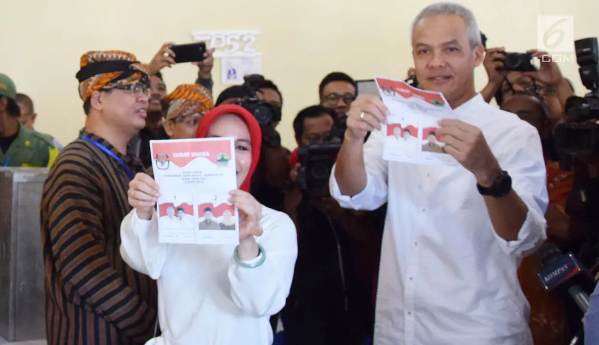 Calon Gubernur Jawa Tengah nomor urut 1, Ganjar Pranowo bersama istri, Siti Atiqoh menunjukkan surat suara pada pelaksanaan Pilkada Serentak 2018 di Tempat Pemungutan Suara ( TPS) 02 Kelurahan Gajahmungkur Kota Semarang, Rabu (27/6). (Liputan6.com/Gholib)