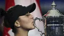 Petenis Kanada, Bianca Andreescu (19) mencium Piala AS Terbuka 2019 usai mengalahkan Serena Williams dari AS di final tunggal putri di New York (7/9/2019). Andreescu menang atas Serena 6-3, 7-5. (AP Photo/Charles Krupa)