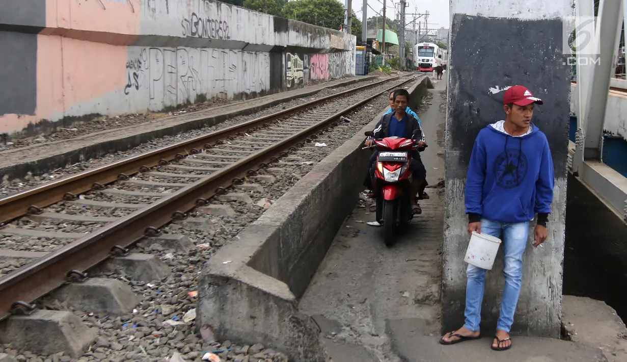 Pengendara melintas di samping kereta yang tengah melintas di kawasan Banjir Kanal Barat, Jakarta, Selasa (20/3). Selain mempersingkat waktu, pengendara beralasan hal itu demi memperpendek jarak tempuh. (Liputan6.com/Arya Manggala)