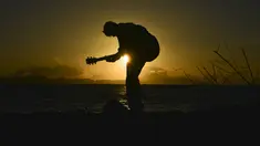 Seorang pria memainkan gitar saat matahari terbenam atau sunset di pantai Banda Aceh pada 28 Juni 2019. Pemandangan makin sempurna saat matahari tenggelam hingga alam berubah semakin remang dan romantis. (Photo by CHAIDEER MAHYUDDIN / AFP)