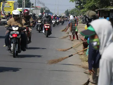 Sejumlah Penyapu jalan (Tawur) berjejer di pinggir jalan untuk mendapatkan uang receh di kawasan Indramayu, Subang, Jabar, Senin (11/7). Uang receh tersebut dilempar pengendara untuk para Tawur di jalur Pantura (Liputan6.com/Herman Zakharia)