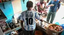 Pemilik warung teh, Shib Shankar Patra sebagai fans timnas Argentina mengenakan jersey saat bekerja di dalam warung tehnya yang dicat dengan warna tim di Ichhapur sekitar 35 km sebelah utara Kolkata pada 12 Desember 2022. Argentina berhasil lolos ke babak semifinal Piala Dunia 2022 Qatar yang akan melawan Kroasia. (AFP/Dibyangshu Sarkar)